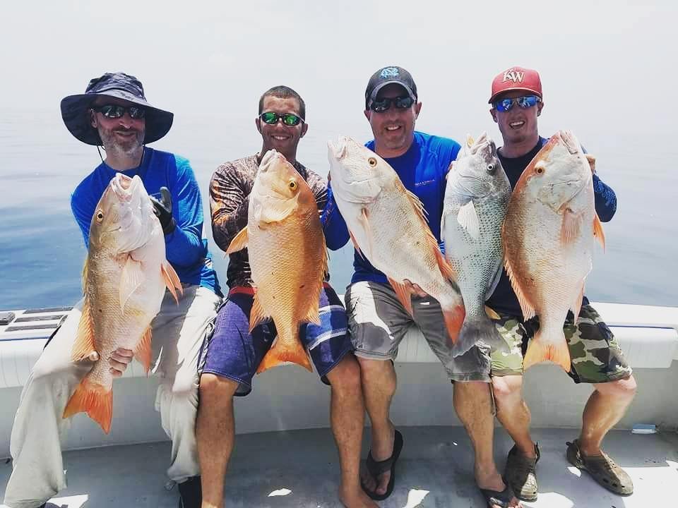A group of four anglers proudly holding large fish caught on a boat, showcasing a successful "big pine key fishing charters" with Fish Daily Charters.