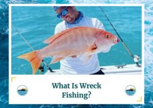 The image shows a smiling angler holding up a large, vibrant red snapper while standing on a boat. The background features clear, turquoise waters, highlighting the beauty of the fishing location. The angler is wearing sunglasses, a hat, and a neck gaiter, indicating a well-prepared fishing trip. The text below reads, "What Is Wreck Fishing?" along with the Fish Daily Charters logo.
