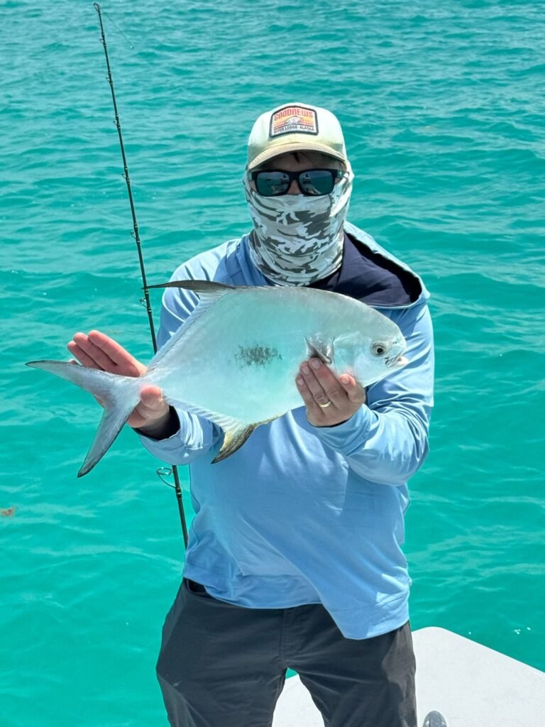 Angler holding a permit fish on a boat during a Permit fishing trip in Key West with Fish Daily Charters, with turquoise waters in the background.