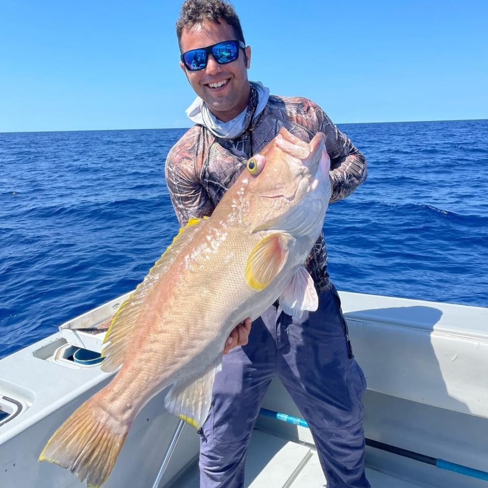 A cheerful angler holding a large Snapper caught on a deep sea fishing charter off the coast of Key West, showcasing the exceptional deep sea fishing packages offered in the region.