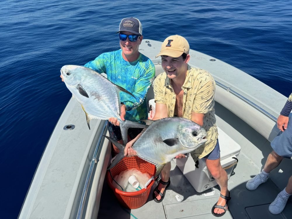 Key West Permit Fishing Charters 1 "Two happy anglers showcasing their impressive catches of permit fish on a boat during a Key West Permit Fishing Charters trip with Fish Daily Charters, surrounded by the calm blue ocean."